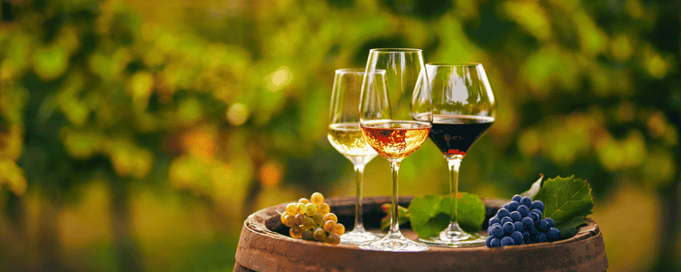 Three glasses of wine with a winery in the back